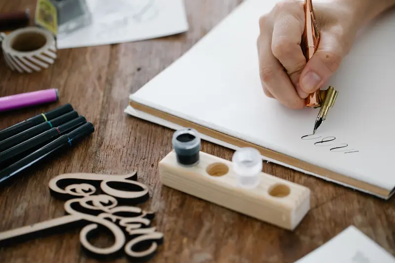 Close-up of hand lettering with a pen and ink on a wooden table, showcasing artistic calligraphy
