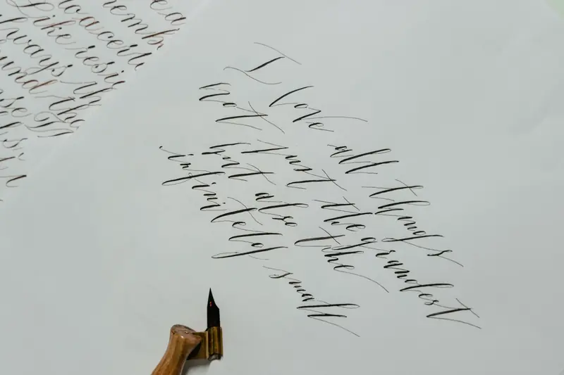 Beautiful calligraphy text written with an ink pen on white paper, showcasing artistic handwriting