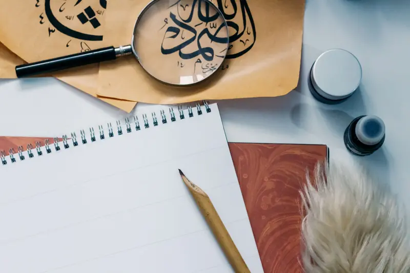 Artistic flat lay of calligraphy tools, notepad, and magnifying glass for creative inspiration