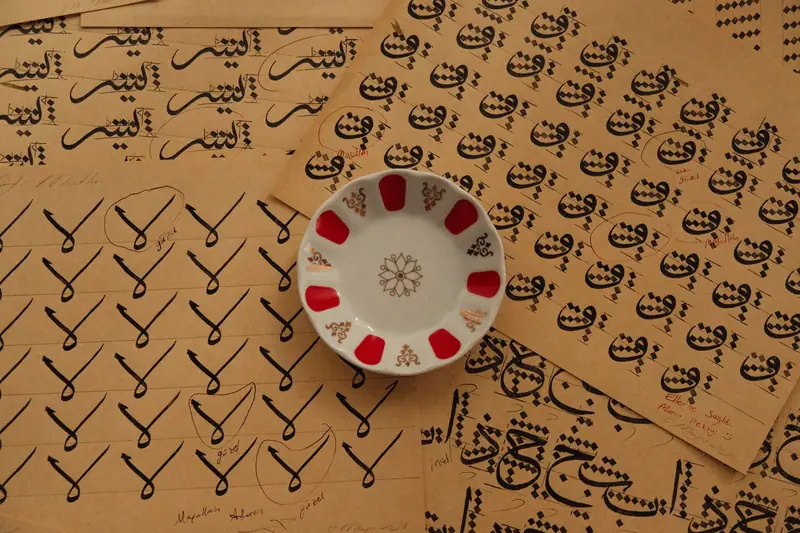 Intricate Arabic calligraphy practice sheets with a decorative plate on brown paper background